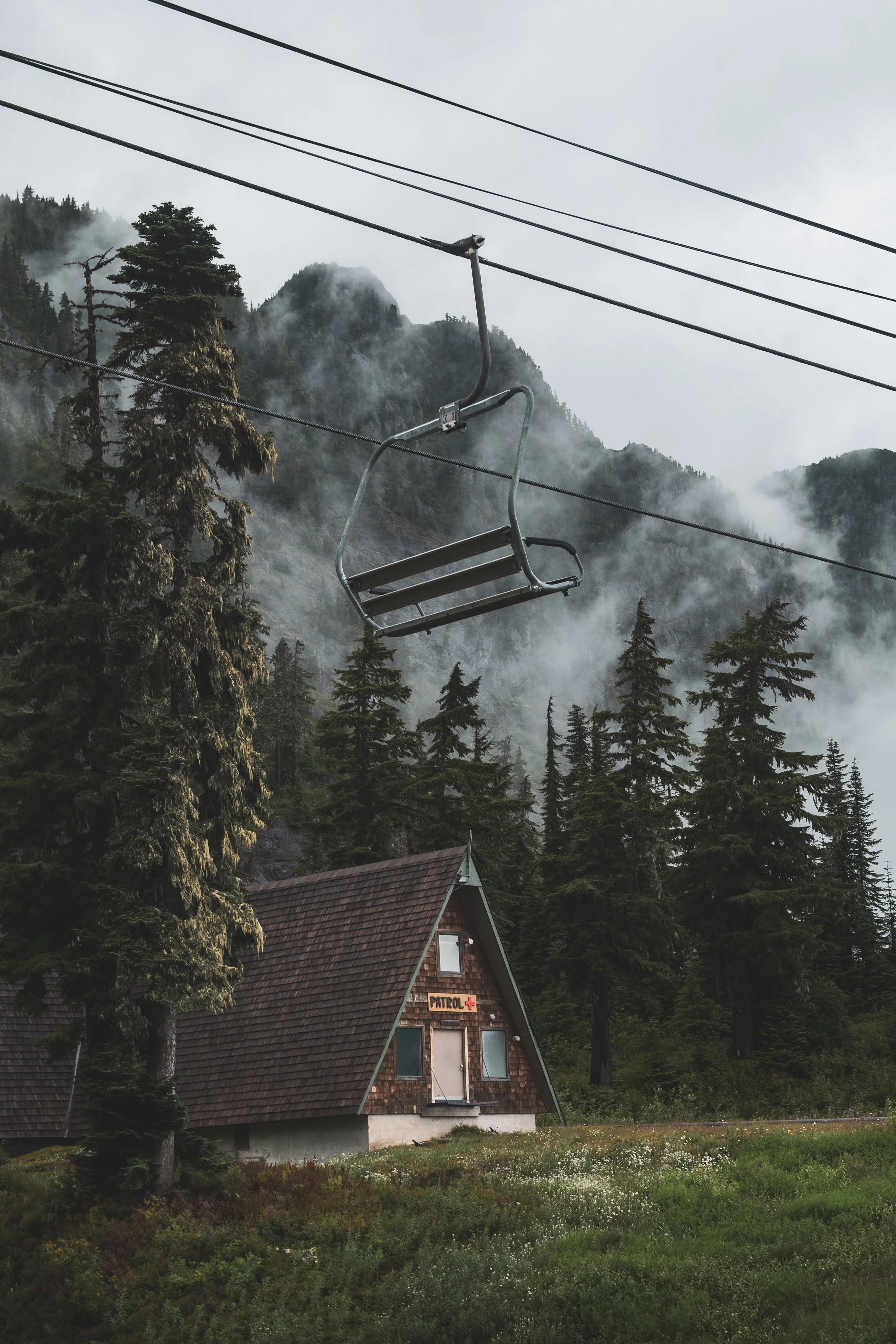 Travel Photography- A Washington mountain landscape with pine trees, fog, and a small wooden house with a shingle roof and a sign that says 'Patrol' and a red cross.