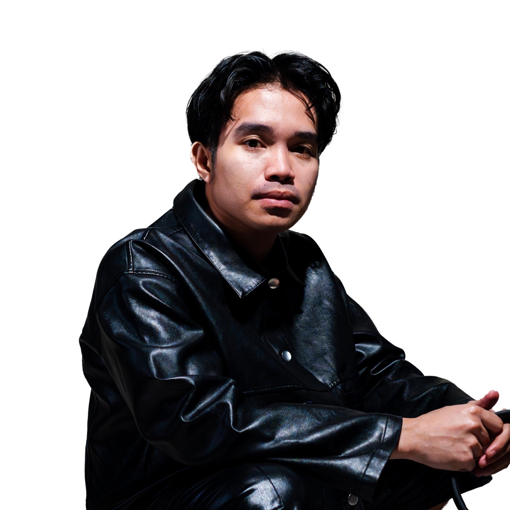 Young man wearing a black leather jacket, sitting against a white background.