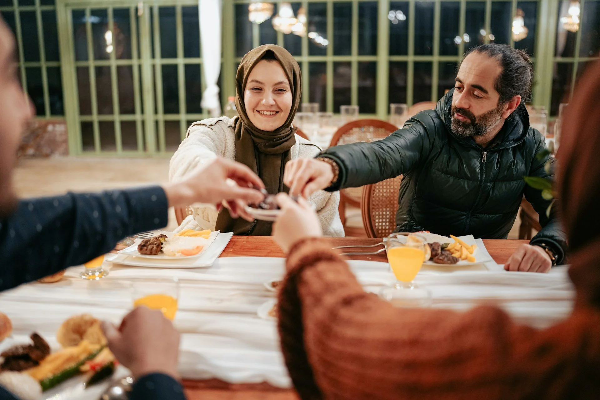 Muslim woman wearing hijab laughing at dinner with her husband and friends