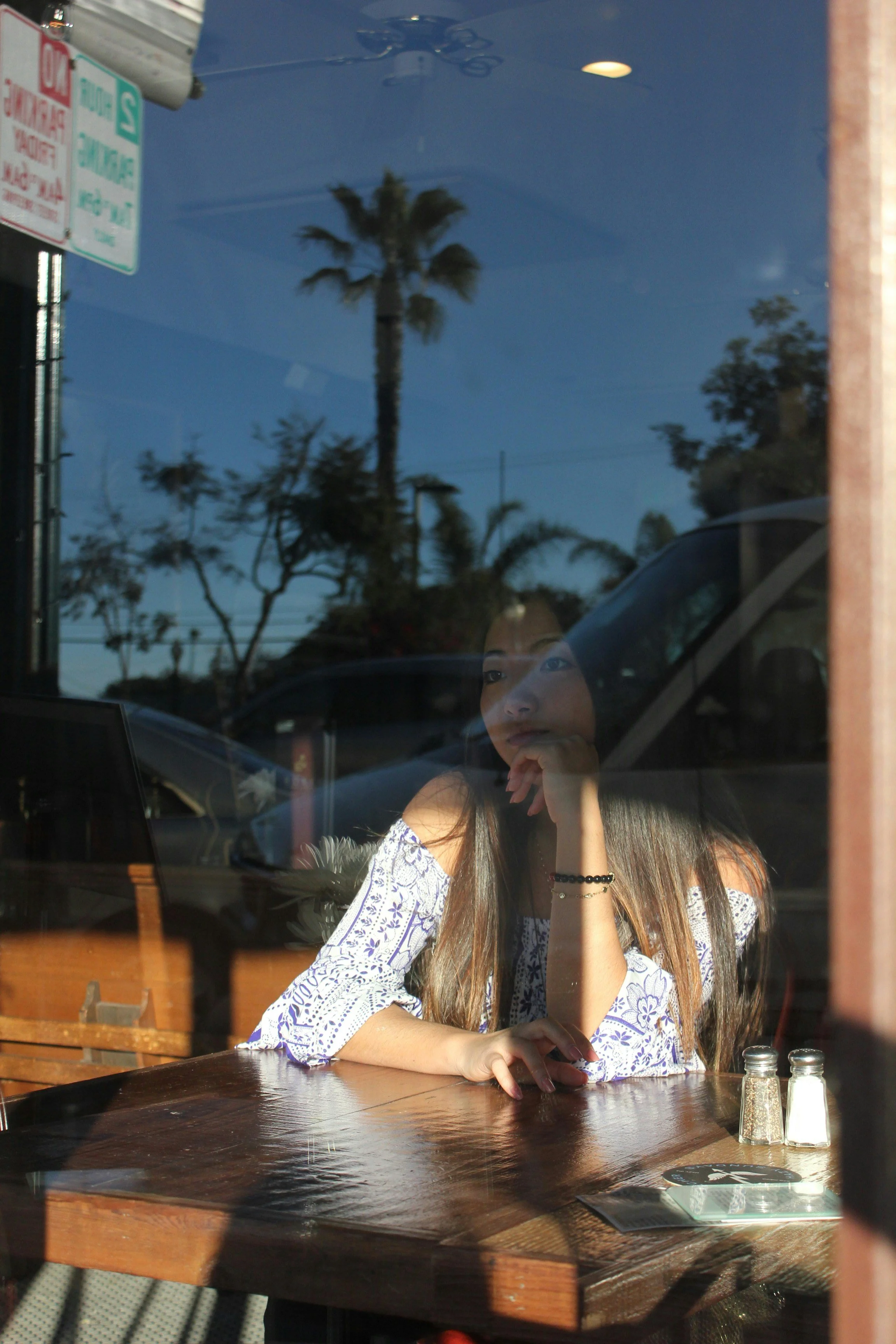 High-achieving woman sitting by a window looking reflective about imposter syndrome