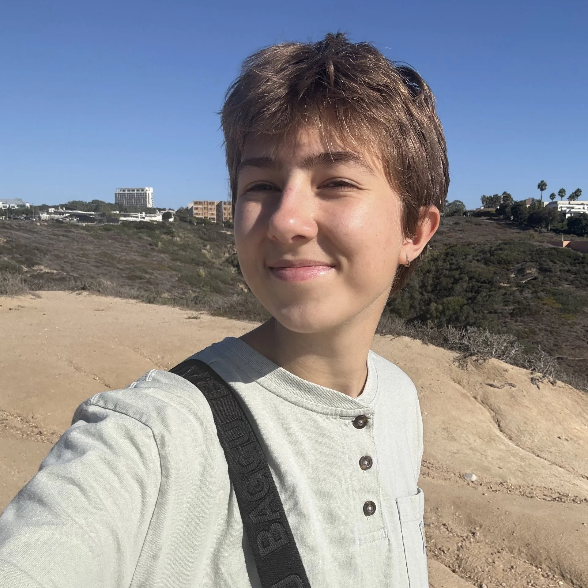 A young woman smiling in the outdoors with the background of some trees