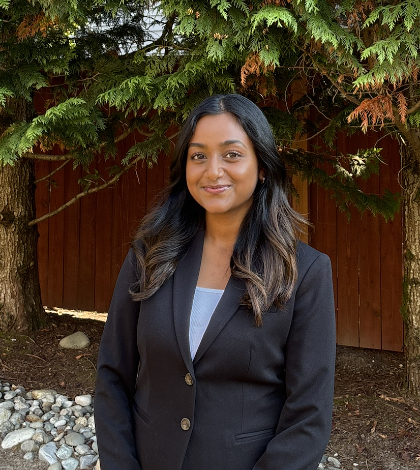 A young woman smiling in the outdoors with the background of some trees