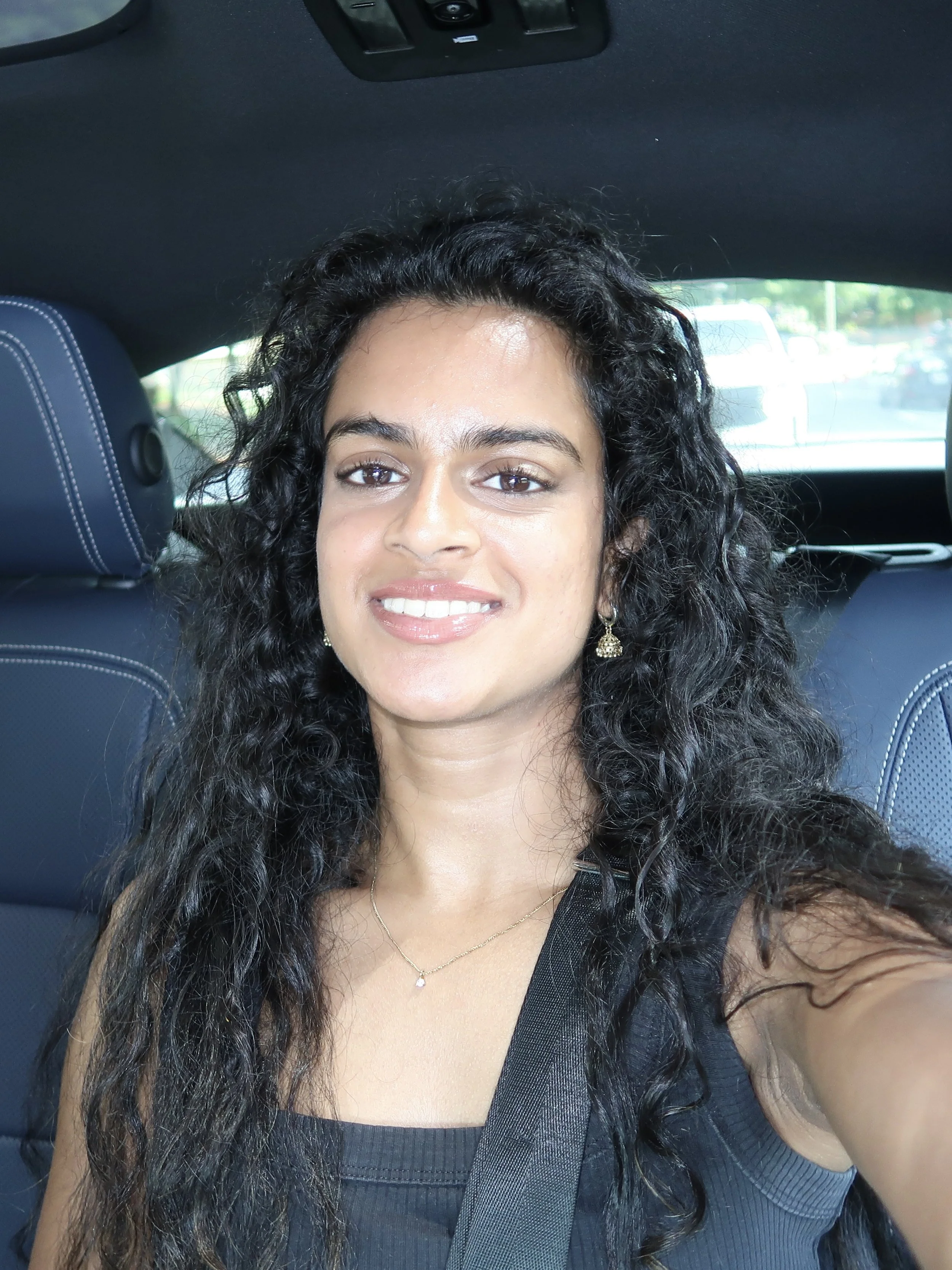 A selfie of a woman smiling in a car