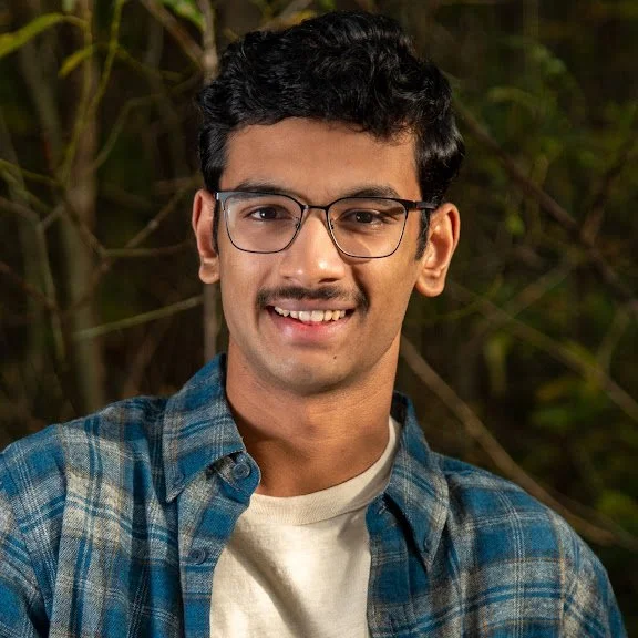 A young man smiling in the background of nature