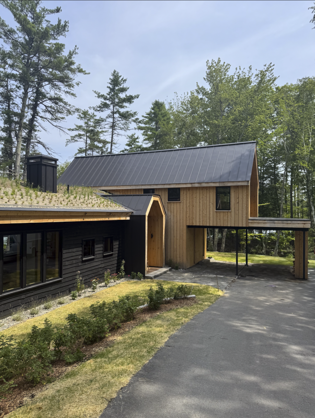 Modern Scandinavian house with car port, cedar siding, and meadow green roof in a forest, Winnipesaukee lake house, New Hampshire