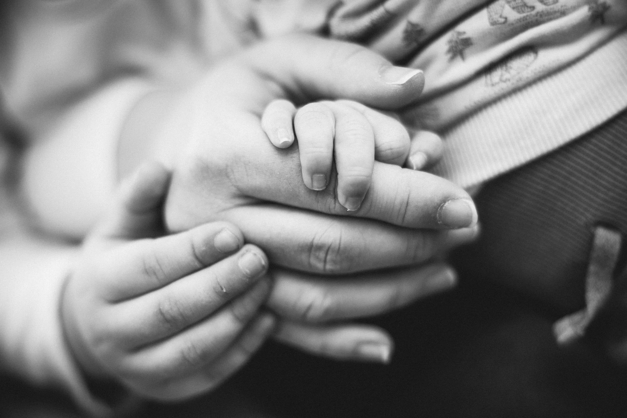 Nahaufnahme von einer kleinen Hand, die eine größere Hand hält, in Schwarz-Weiß