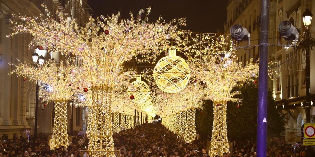 Luces de Navidad en Sevilla 2025 en la Avenida de la Constitución, con miles de personas disfrutando del espectáculo luminoso bajo árboles y bolas gigantes iluminadas.