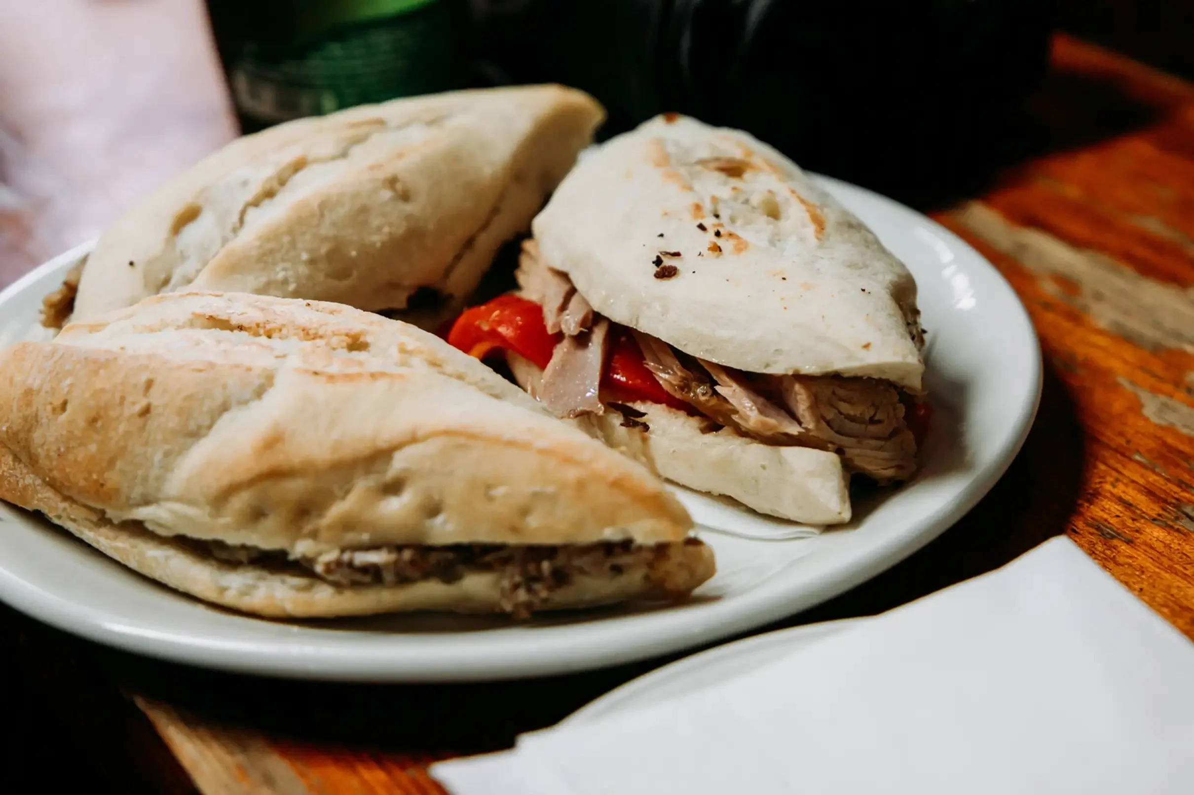Montaditos tradicionales servidos en un bar durante un tour de tapas en Sevilla, con pan crujiente relleno de carne y pimientos en una taberna típica andaluza.
