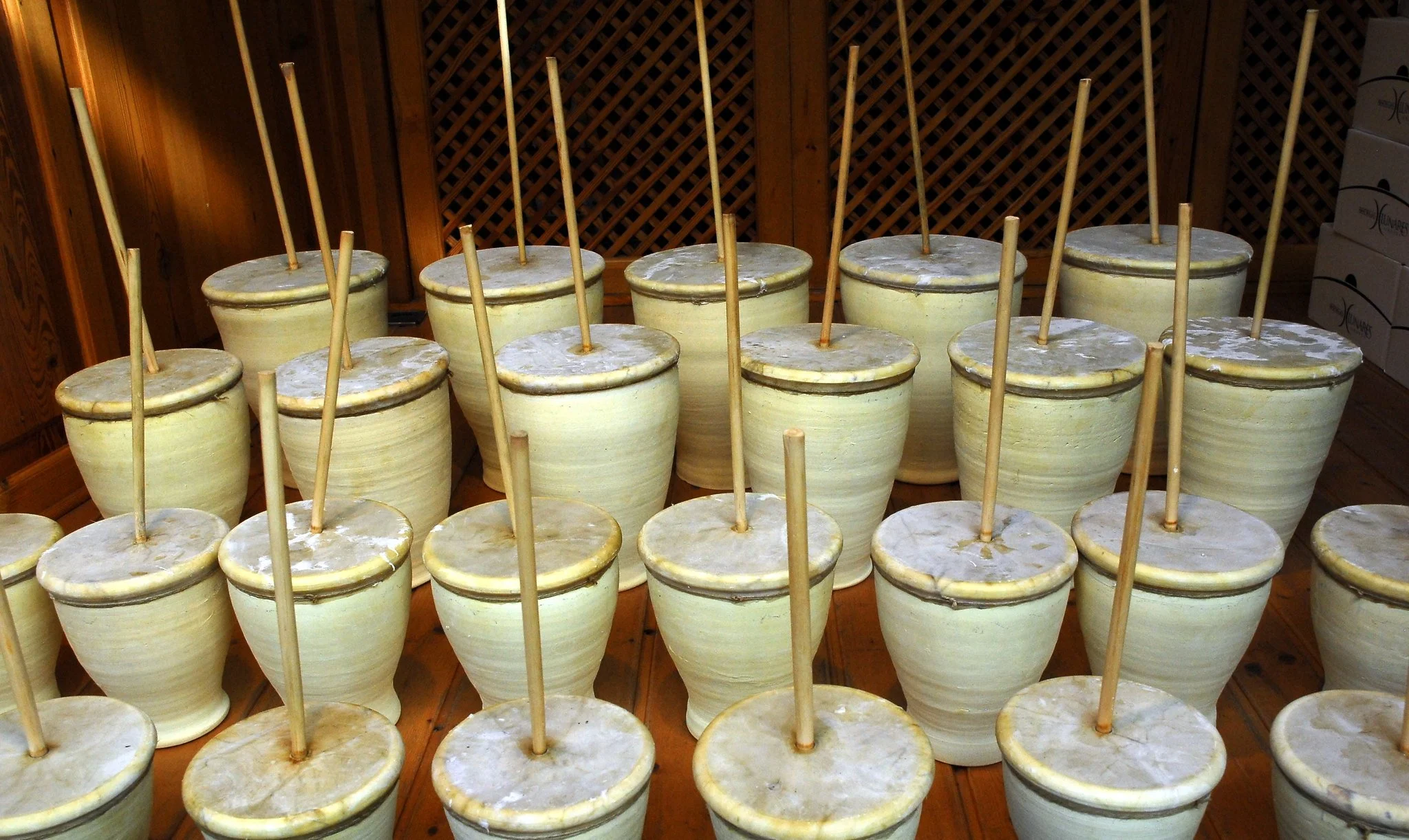 Zambombas tradicionales andaluzas alineadas sobre suelo de madera, listas para tocar en zambombas flamencas en Sevilla durante la Navidad.