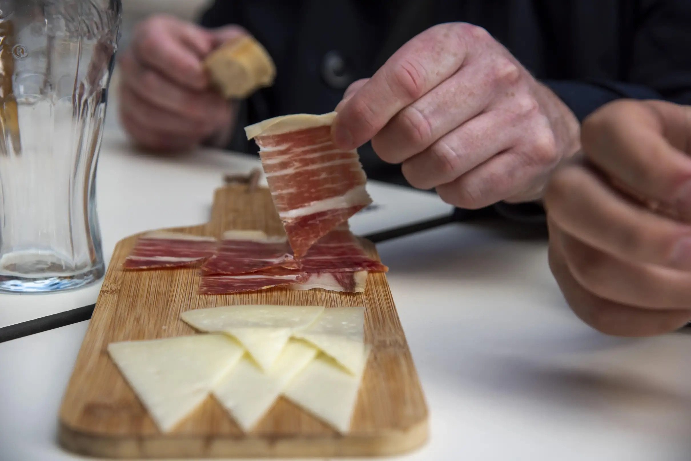 Grupo disfrutando de tapas y bebidas en una ruta gastronómica por Sevilla guiada por un lugareño en bares tradicionales del centro histórico.