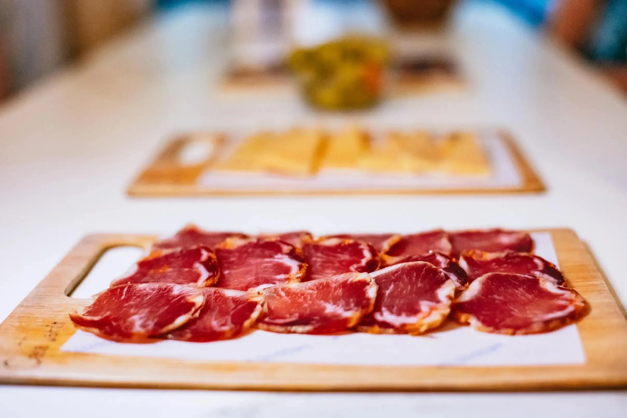 Tabla de jamón ibérico cortado en finas lonchas durante una ruta de tapas en Sevilla, acompañado de quesos y encurtidos en una experiencia gastronómica andaluza.
