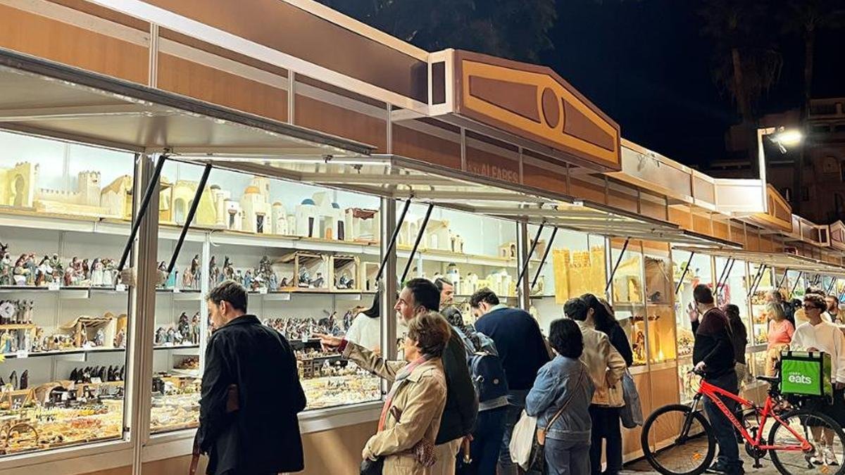 Puestos del Mercado de Belenes de Sevilla en Navidad, con visitantes comprando figuras artesanas para nacimientos y decoraciones navideñas.