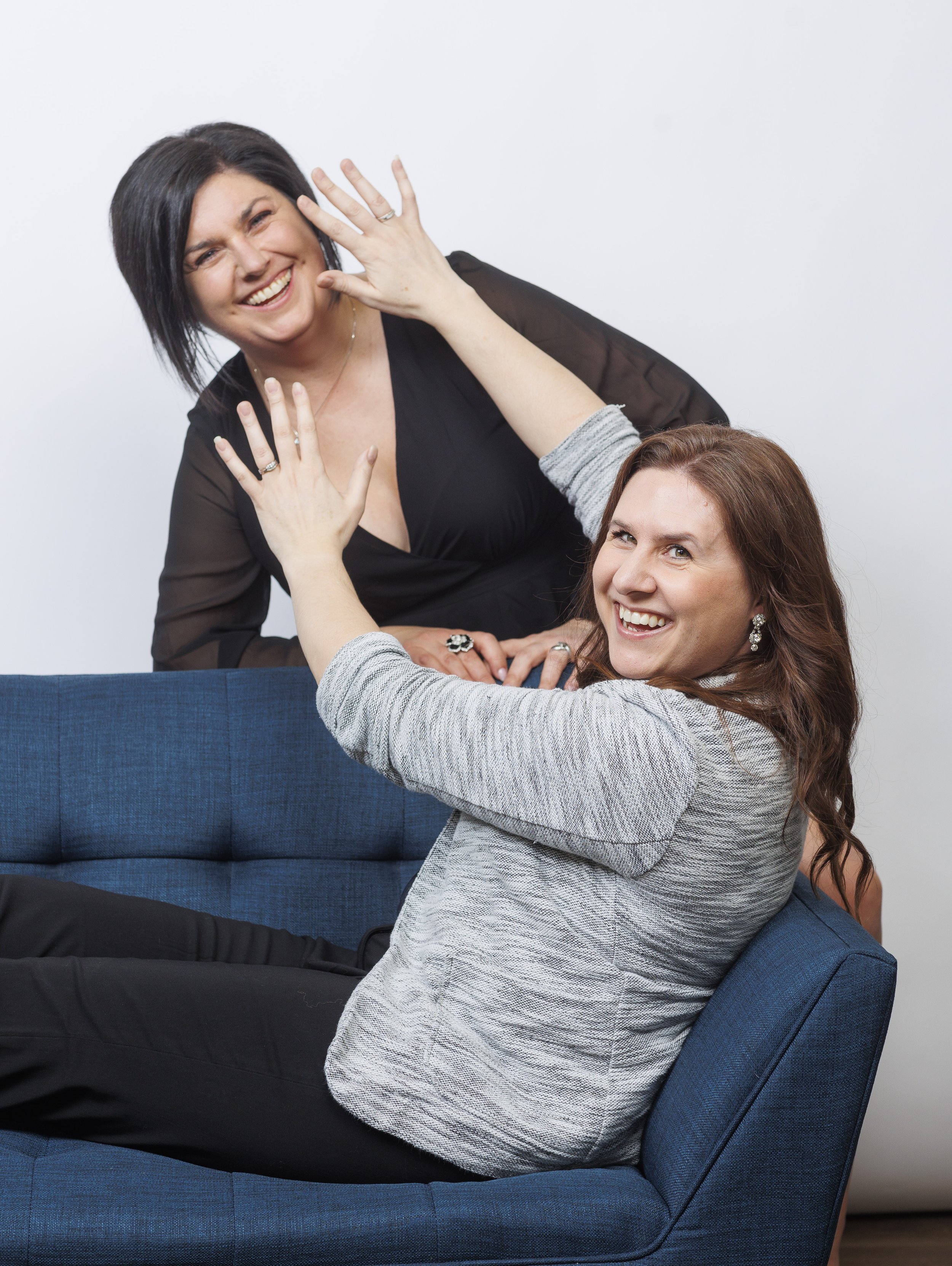 Lindsay Fuchs, co-founder of Undercover Creators, sitting on a blue couch and playfully pretending to block her business partner, Krystal Thorhaug, from the frame, showing a lighthearted and collaborative partnership.