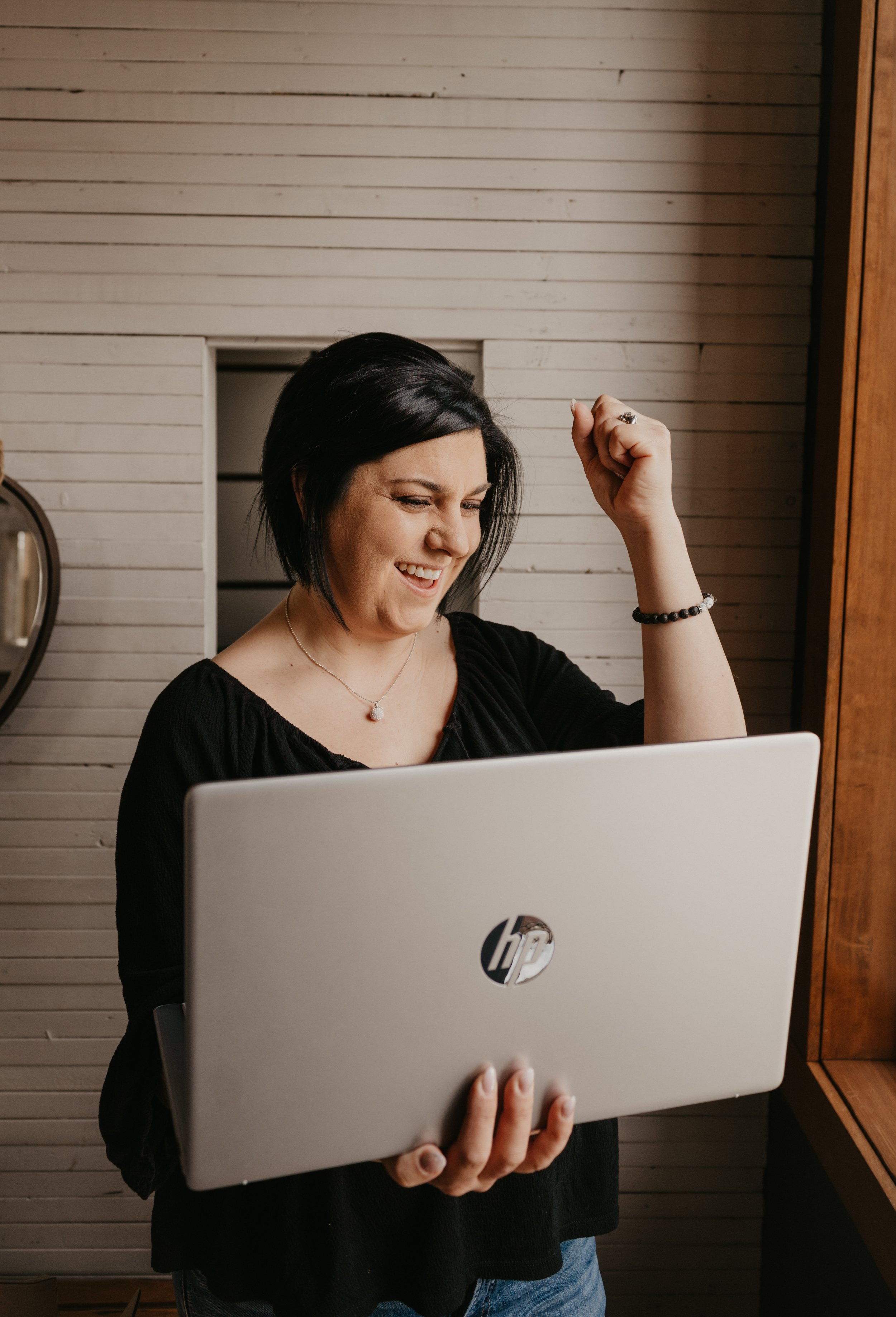 Krystal Thorhaug, co-founder of Undercover Creators, celebrating a win while holding a laptop, representing momentum and confidence in content and marketing strategy.
