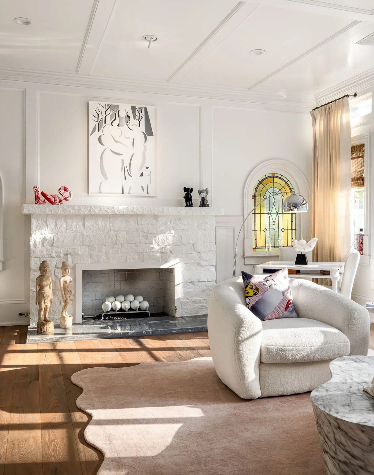 A large fireplace catches afternoon light in a living room decorated with modern furniture.