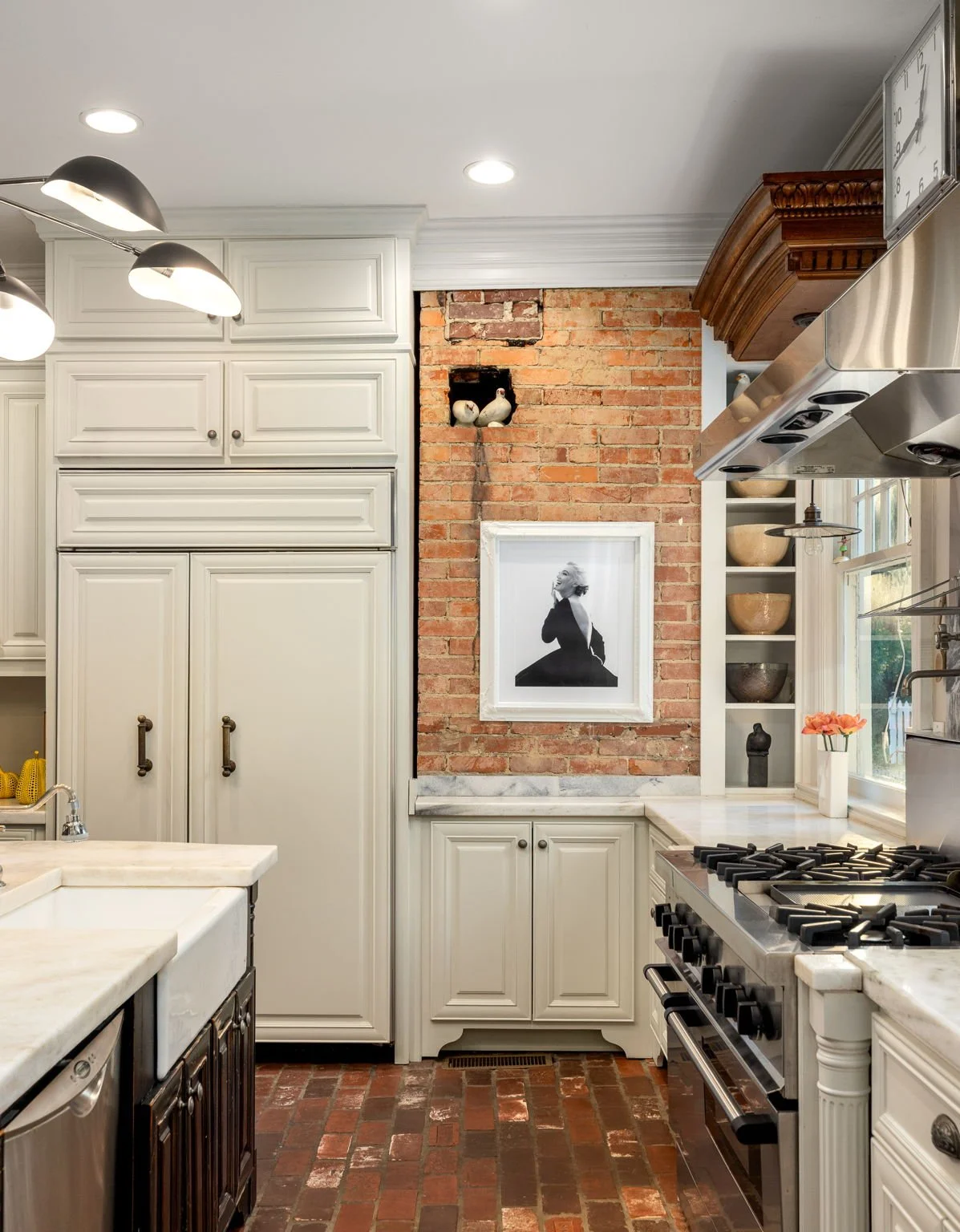 A renovated kitchen with exposed brick and high-end appliances and marble countertops.