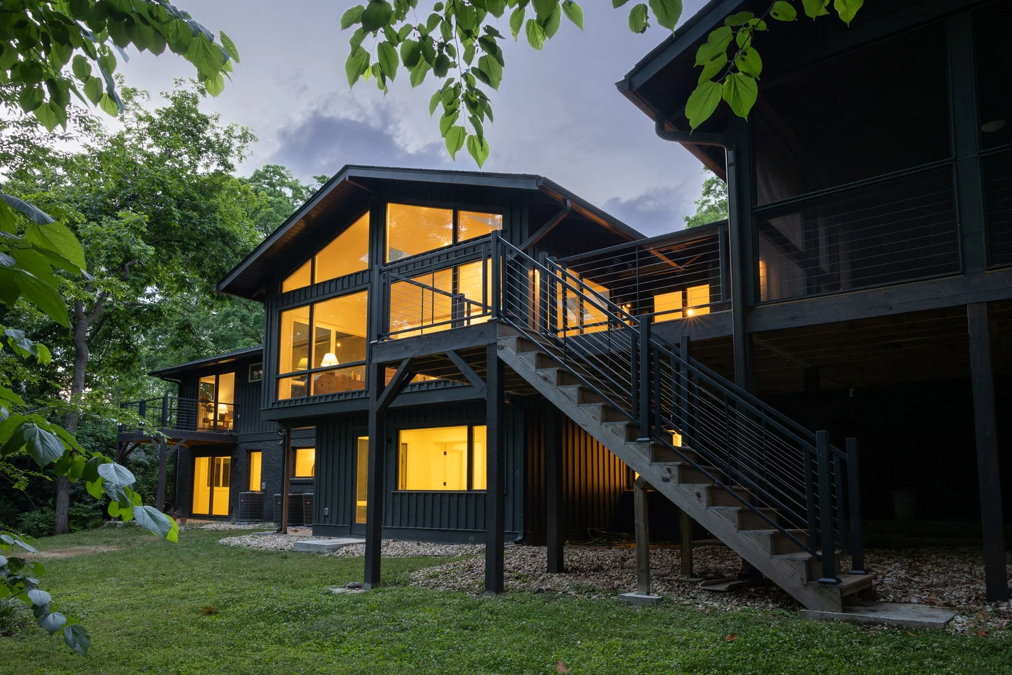Large glowing windows illuminate this Buckhead Atlanta midcentury modern's rear exterior, photographed at dusk.