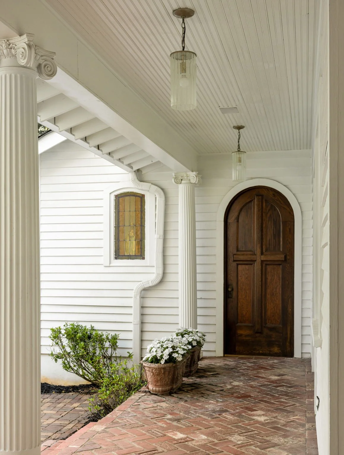 A beautiful arched doorway and stained glass at the end of herringbone brick walkway.