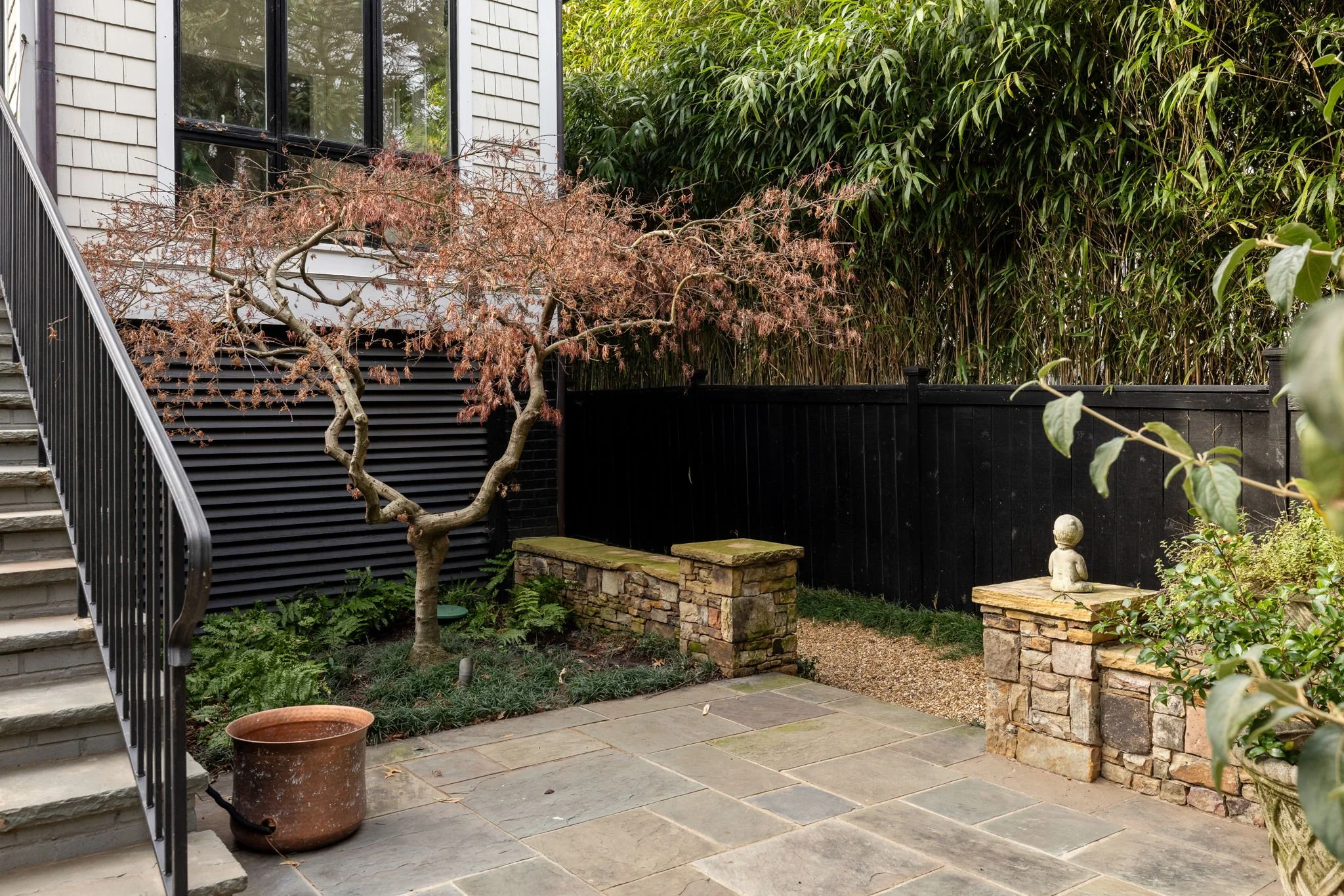 A quiet sitting area with a Japanese maple and stone tile.