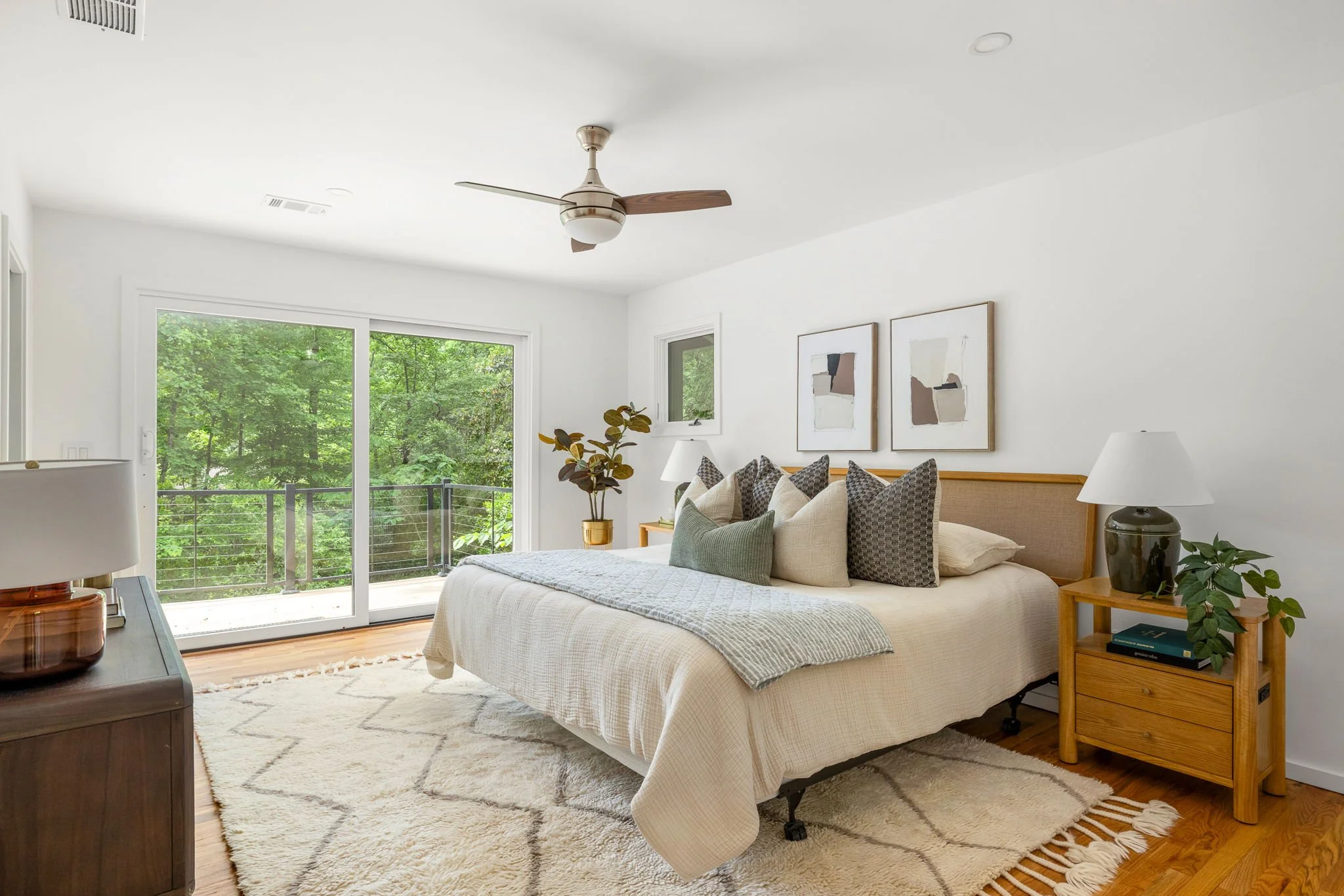 A primary bedroom full of natural light and views of the surrounding forest.