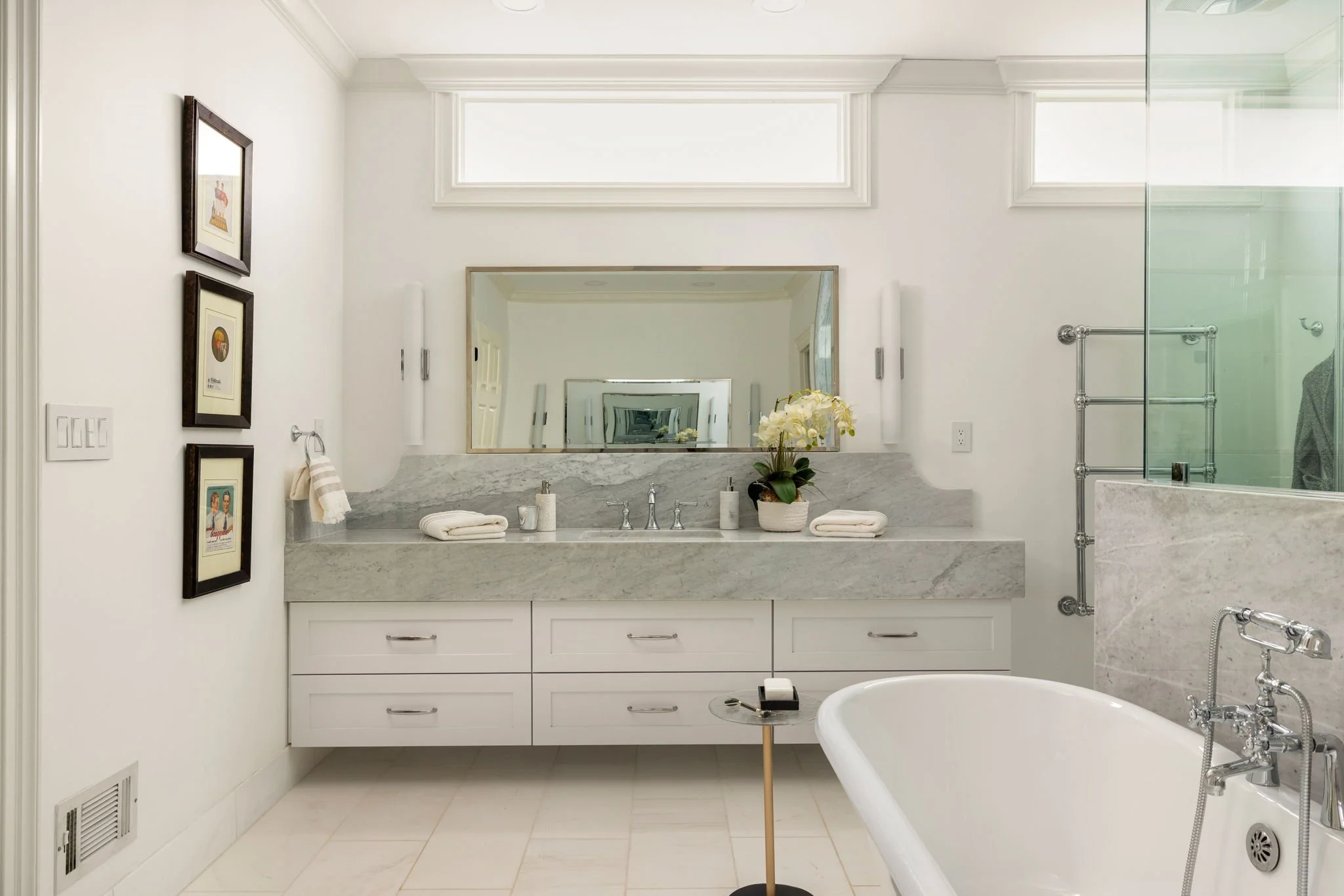 A clawfoot tub and marble countertops in this masculine primary bathroom.