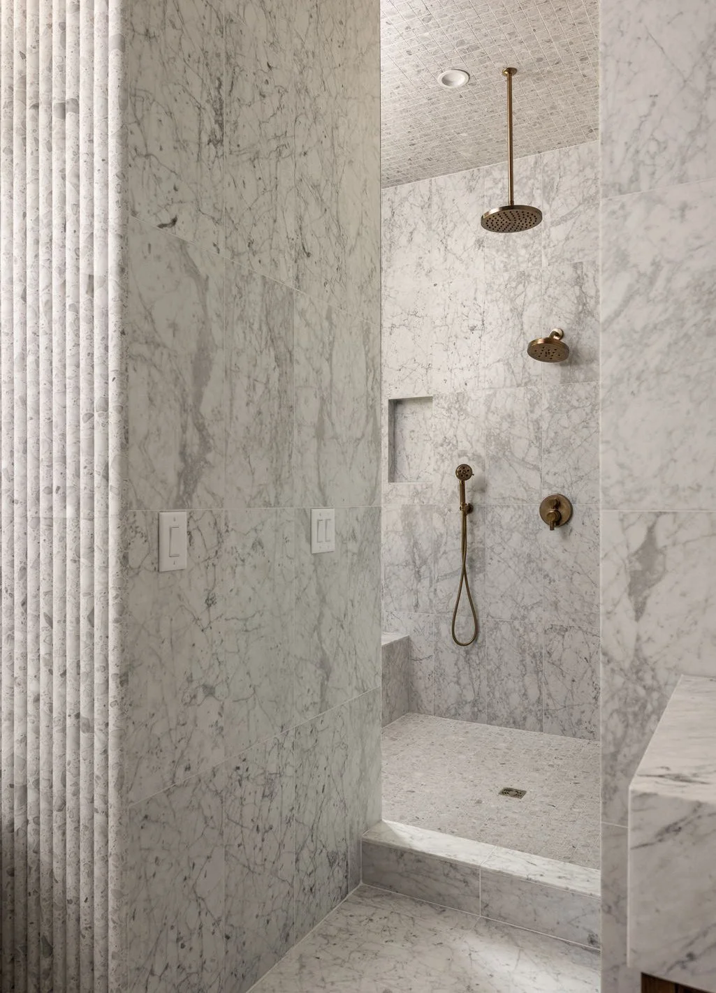 Spa-style bathroom with floor-to-ceiling marble tile, a walk-in shower, and brass fixtures