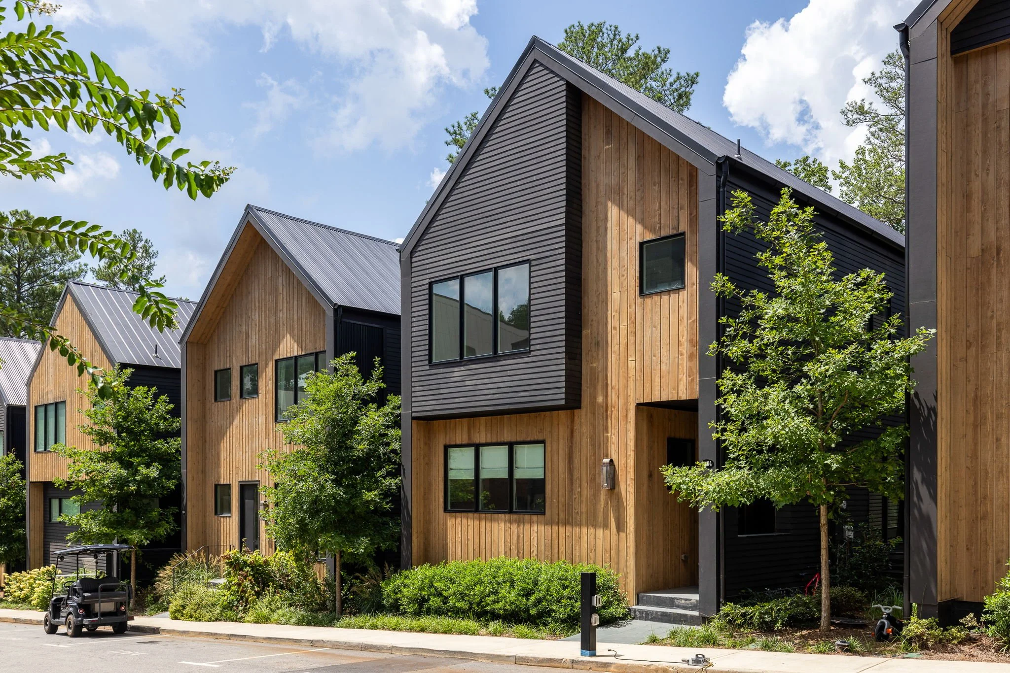 Modern house incorporating multiple materials such as wood and metal, in a close golf cart community.