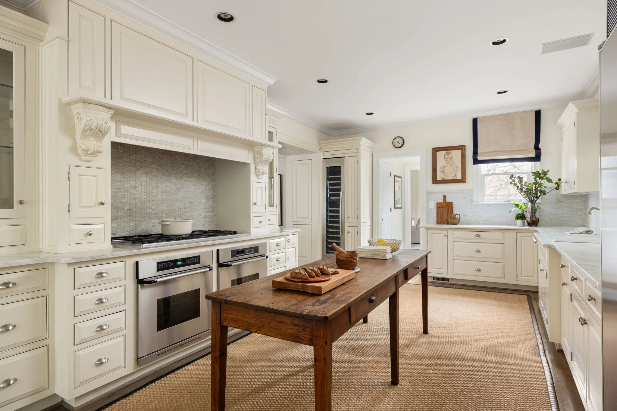 Ornate cabinetry and high-end appliances mix with antique furniture in this bright kitchen.