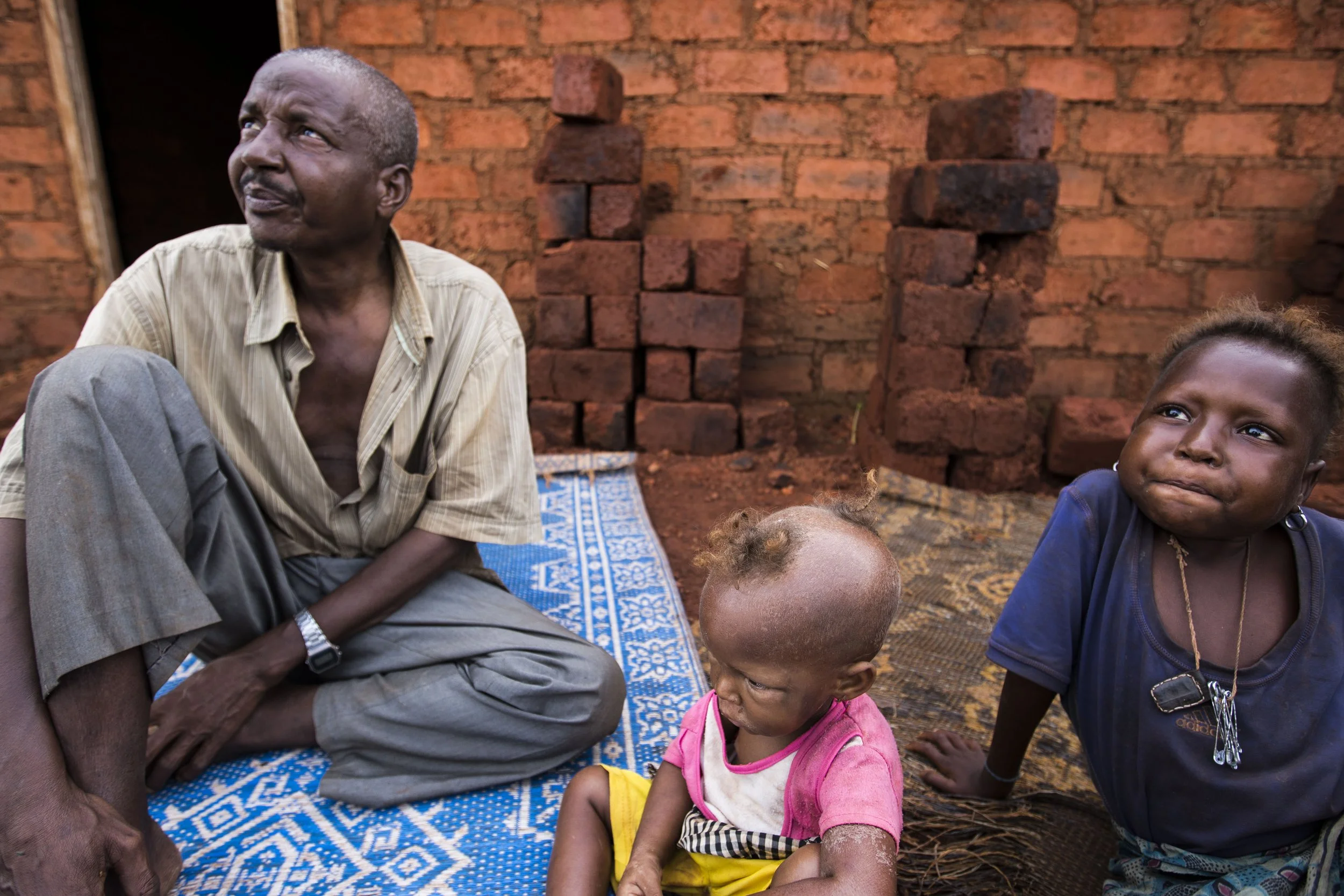 Moussa with his two surviving daughters on a new site in Yaloke built to resettle the Peulh community despite the majority's wish to get evacuated out of the village.