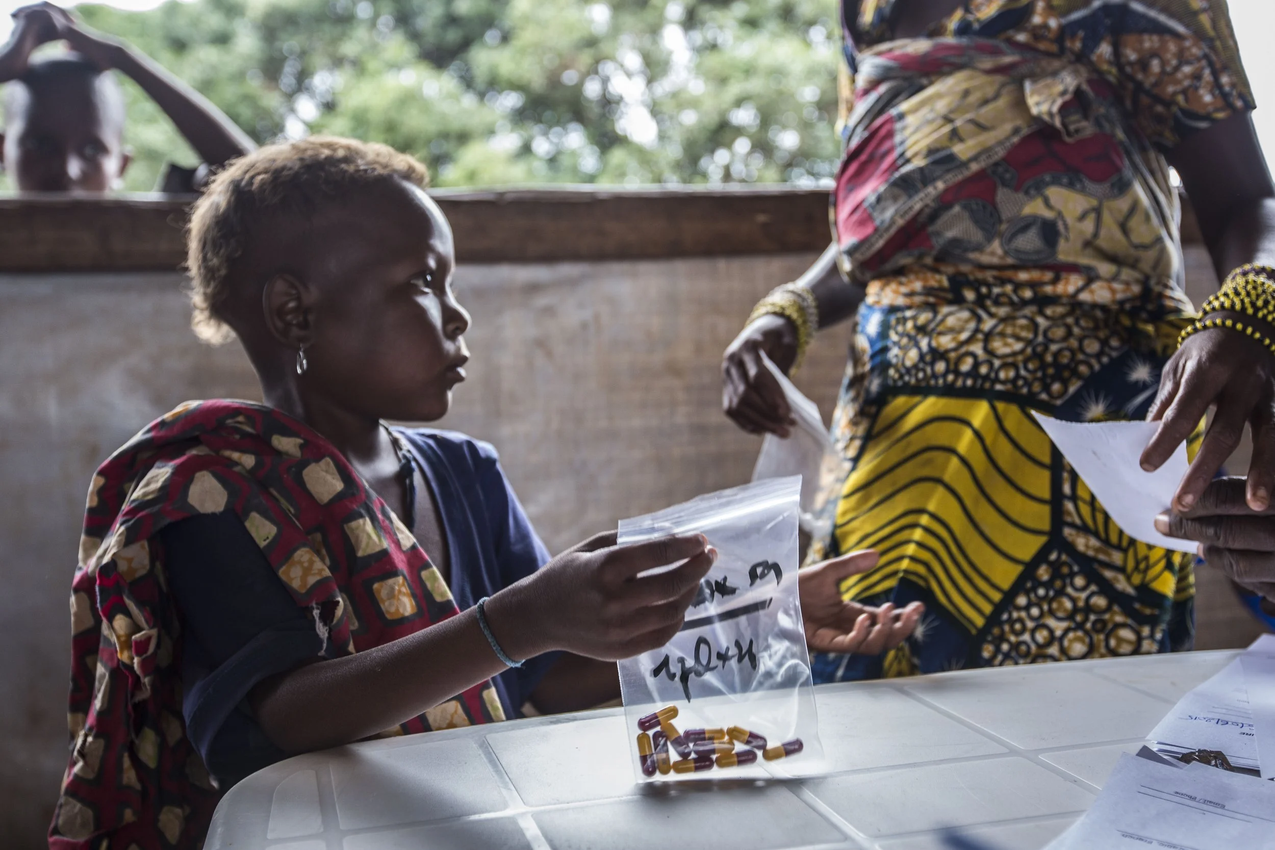 8 years old Awa with her mother Halima picking up malnutrition treatment pills for herself and her younger sister Rachida.