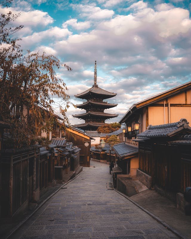 The Gion Pagoda (Yasaka Pagoda) in Kyoto, standing tall against the skyline, with its multi-tiered wooden structure surrounded by traditional Japanese buildings and lush greenery.
