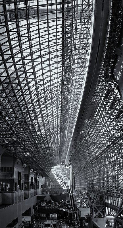 Close-up view of the modern, futuristic glass and steel roof of Kyoto Station, featuring an intricate grid pattern and open space, allowing natural light to flood the interior.