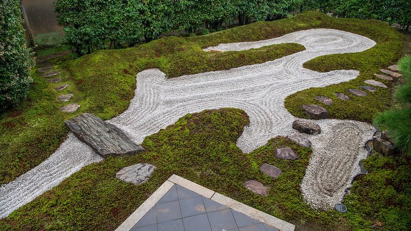 A Zen garden at Daitokuji Temple, featuring meticulously arranged rocks, raked gravel, and sparse vegetation, designed to promote meditation and contemplation in a tranquil setting.
