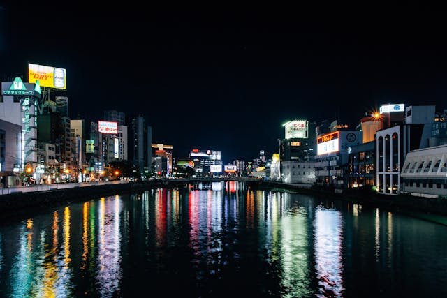 Night view of Tokyo with skyscrapers reflecting on the calm water, creating a stunning cityscape with glowing lights and vibrant reflections.