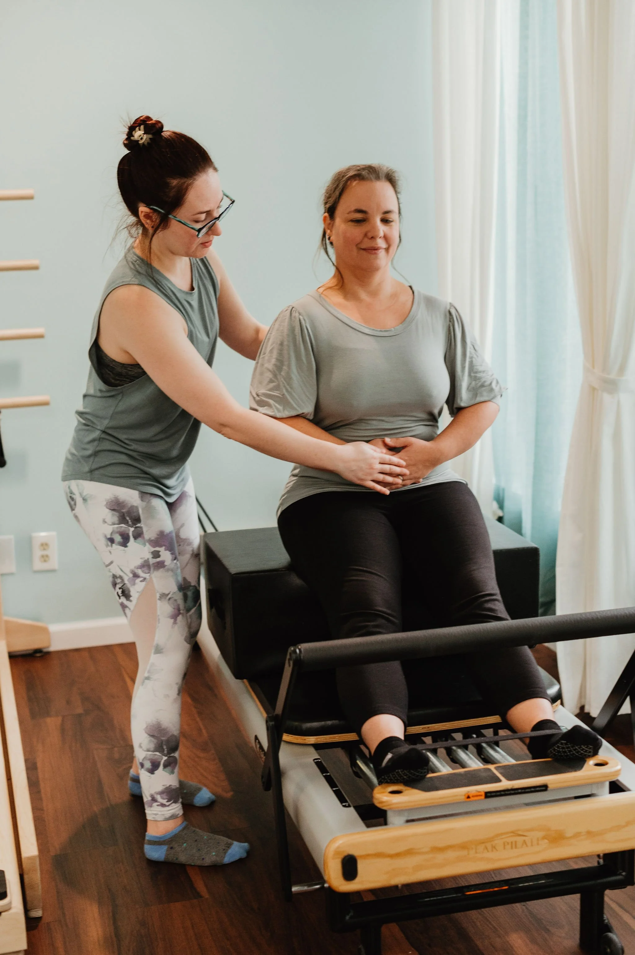 Sara Kali providing expert hands-on adjustments to ensure proper form during a private Pilates session.