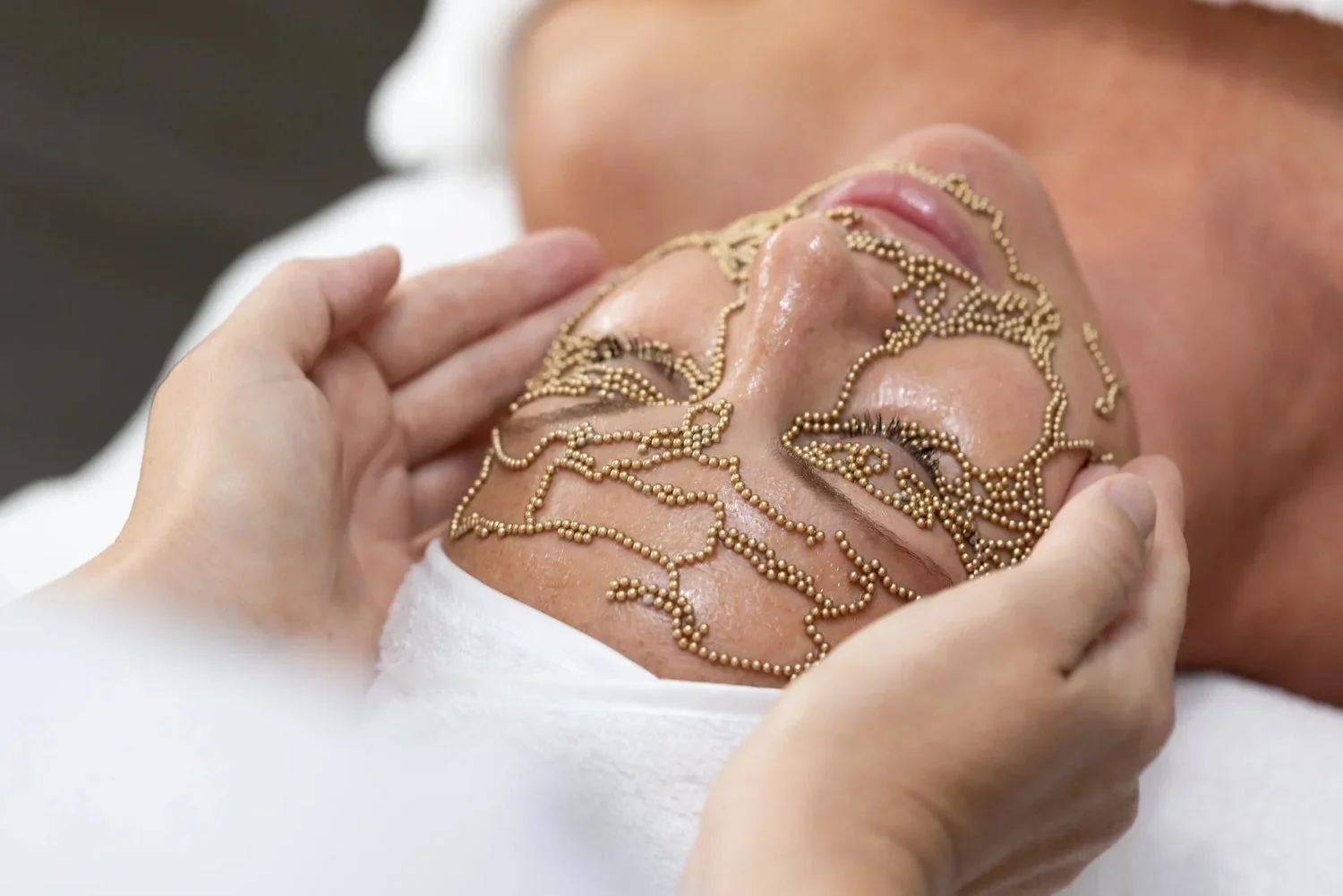 A Qi Beauty facial treatment using gold-plated magnets to support skin cell recovery and lifting.