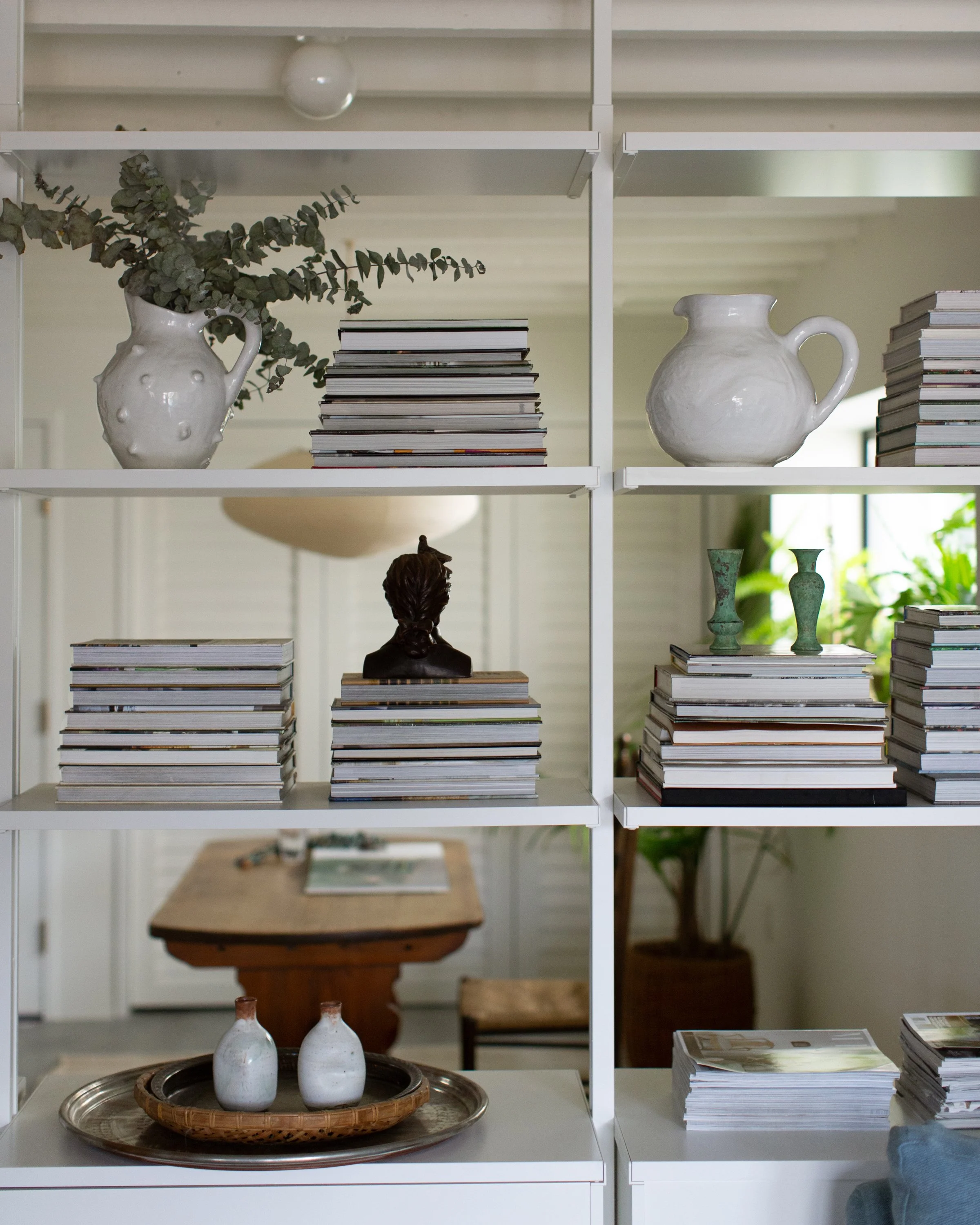 Closeup view of room divider book shelving, showing stacks of books and vases.
