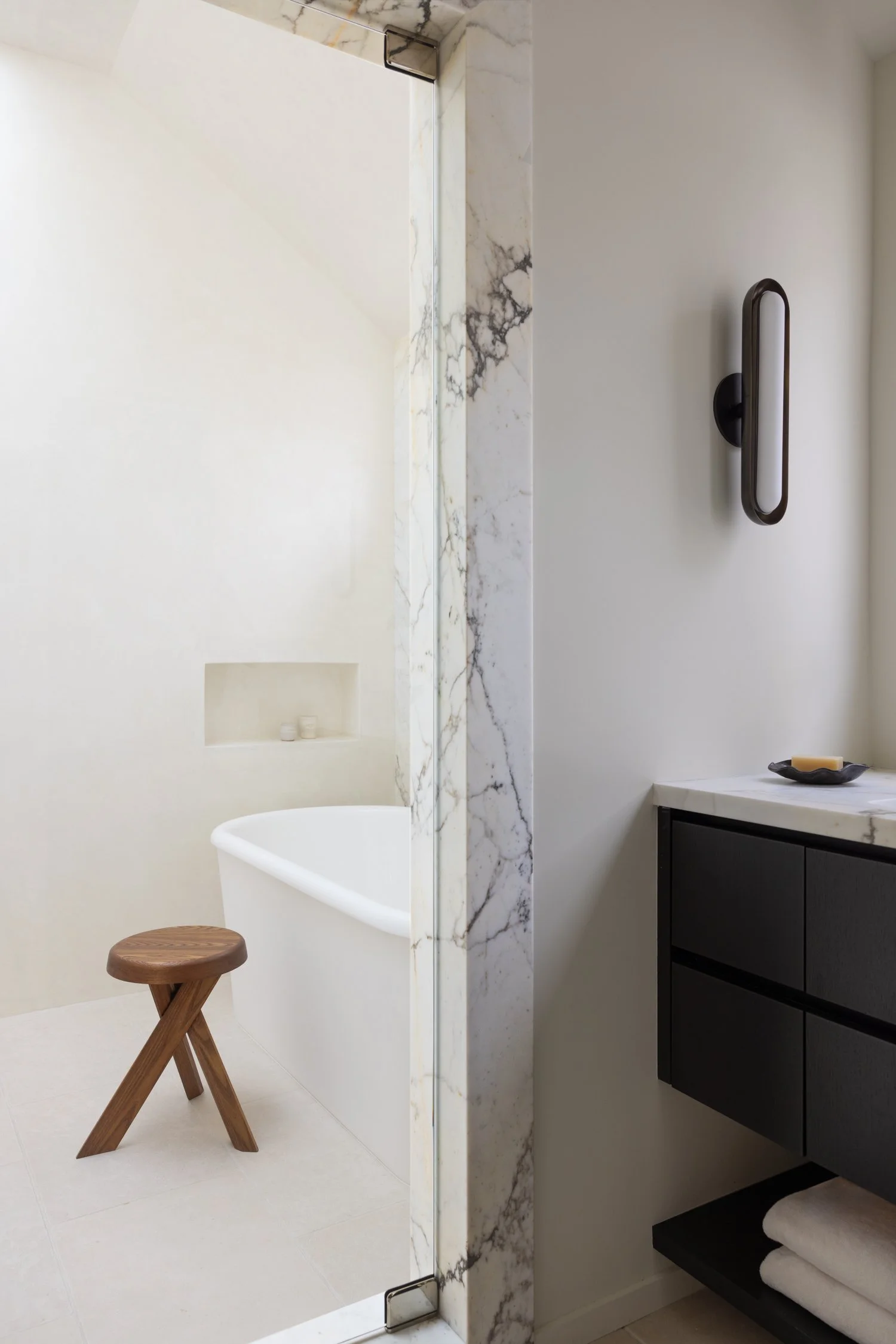 Bathroom closeup showing the bath tub and wooden stool and the sink.
