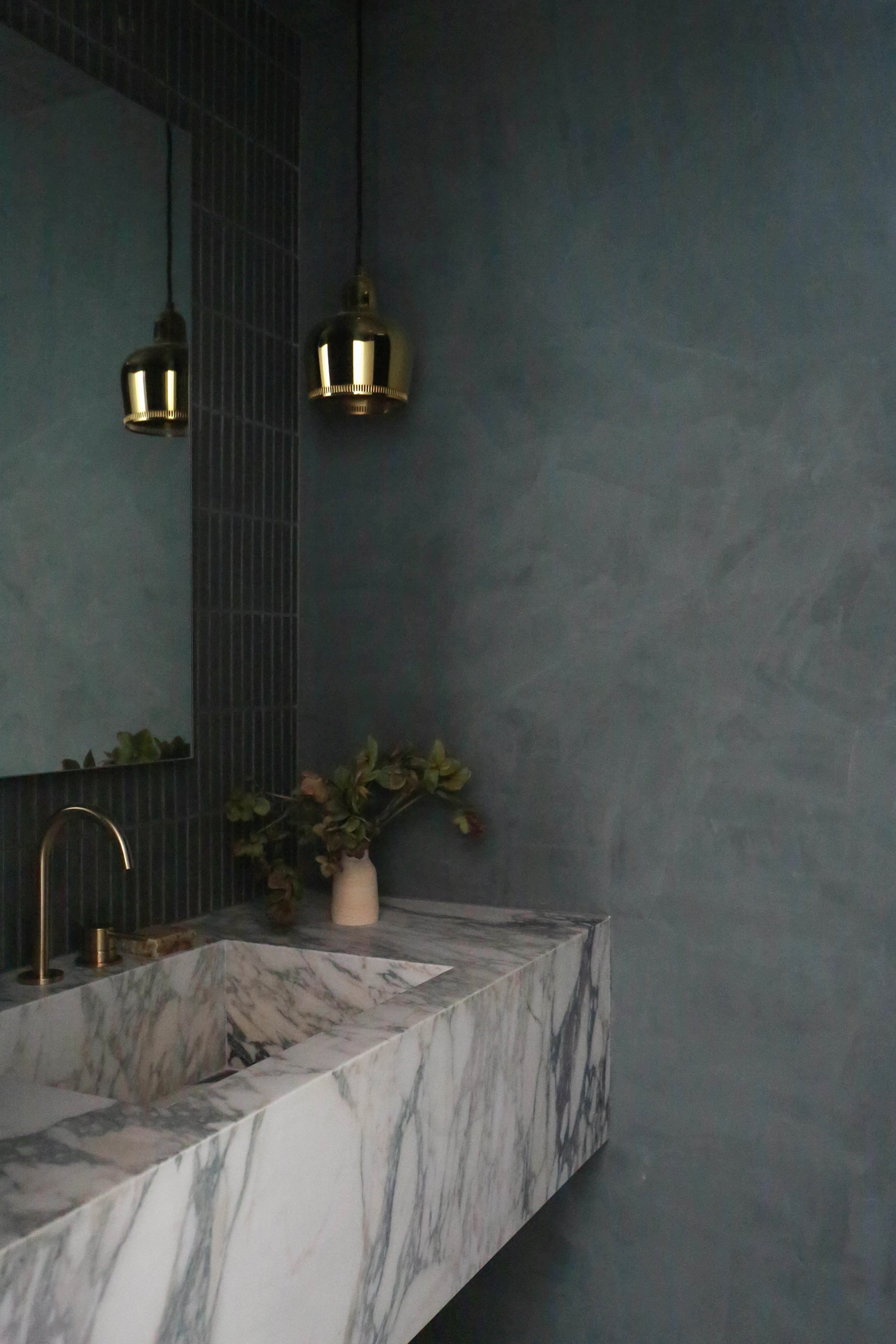 Powder room view showing a sink, ceiling lamp, mirror, vase with flowers.