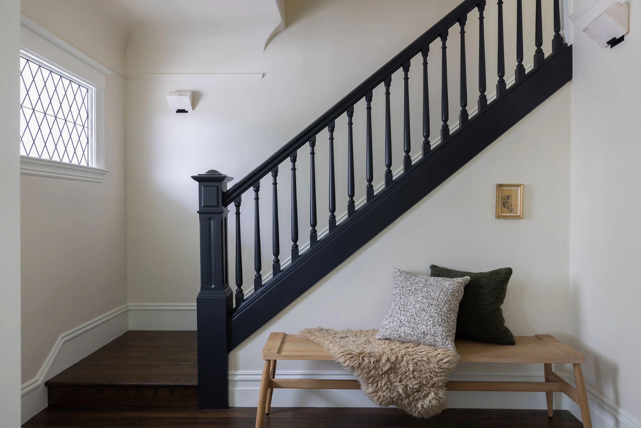 View of the entry showing a bench with decorative pillows, with the staircase behind it.