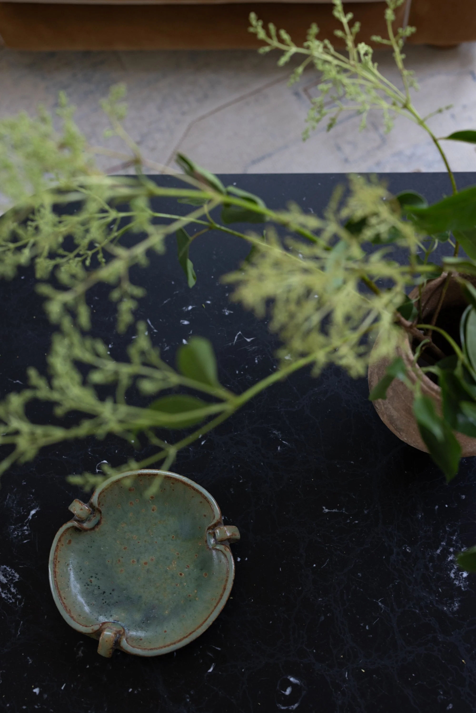 Closeup view of the coffee table, showing a vase with branches and a bowl.