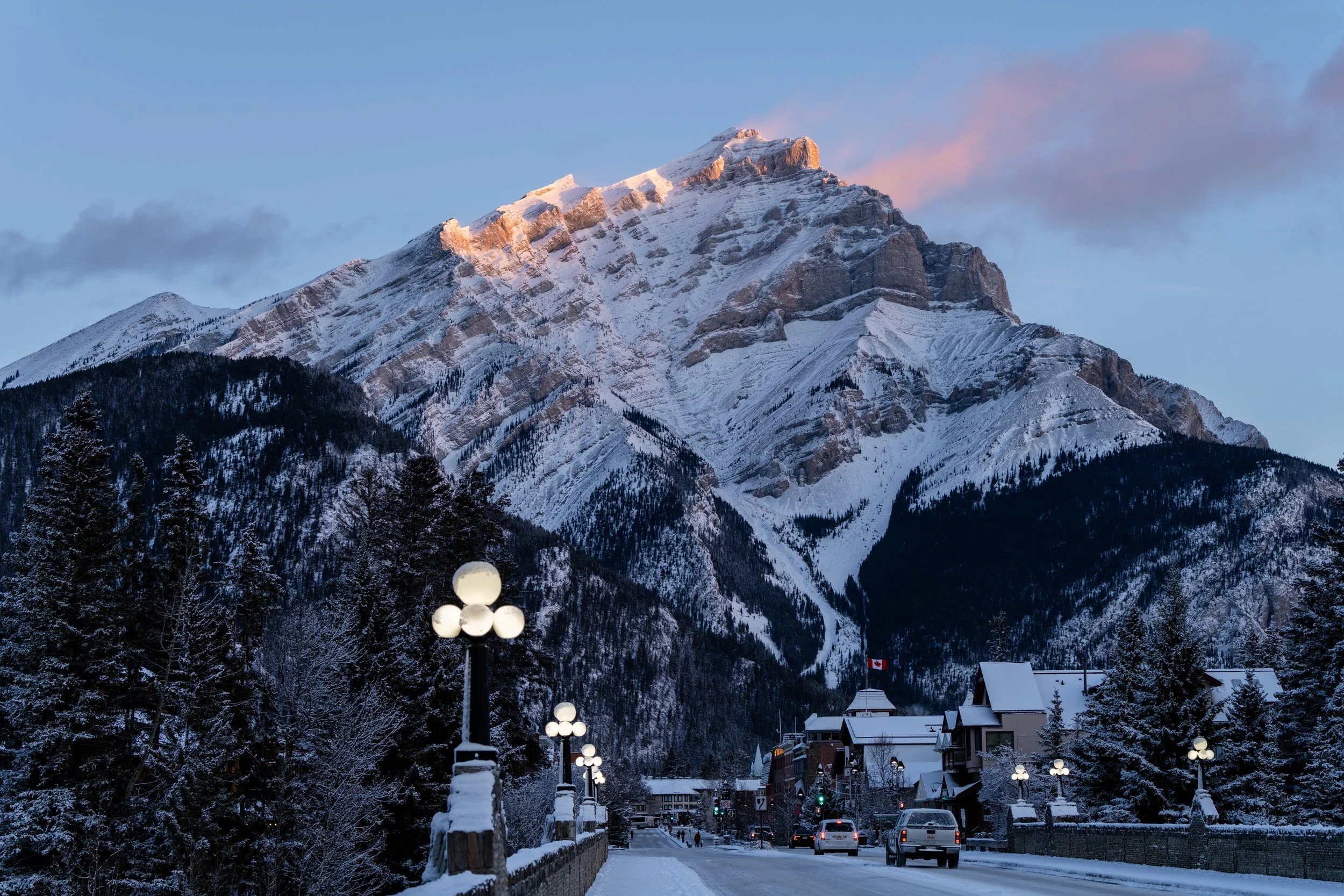 Snow-covered mountain with a small town and streetlights at sunset