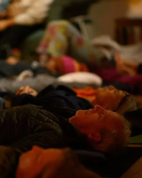 A mixed gender group of people lying down on yoga mats, relaxing or meditating during a sound bath