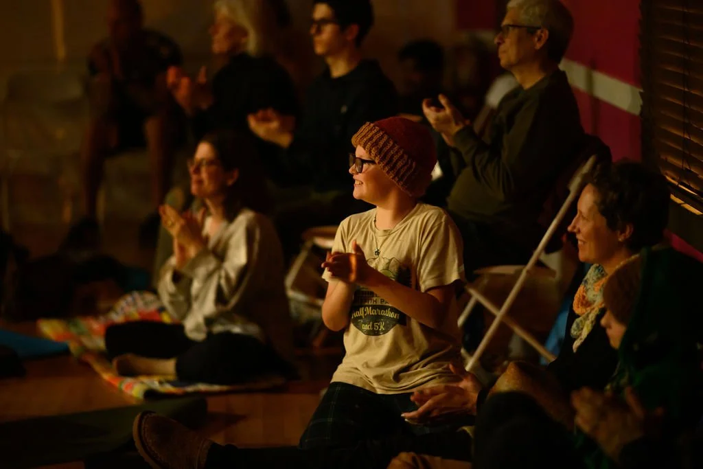 A family with multiple generations enjoying a live performance in an intimate setting, lit by warm glow of candles.