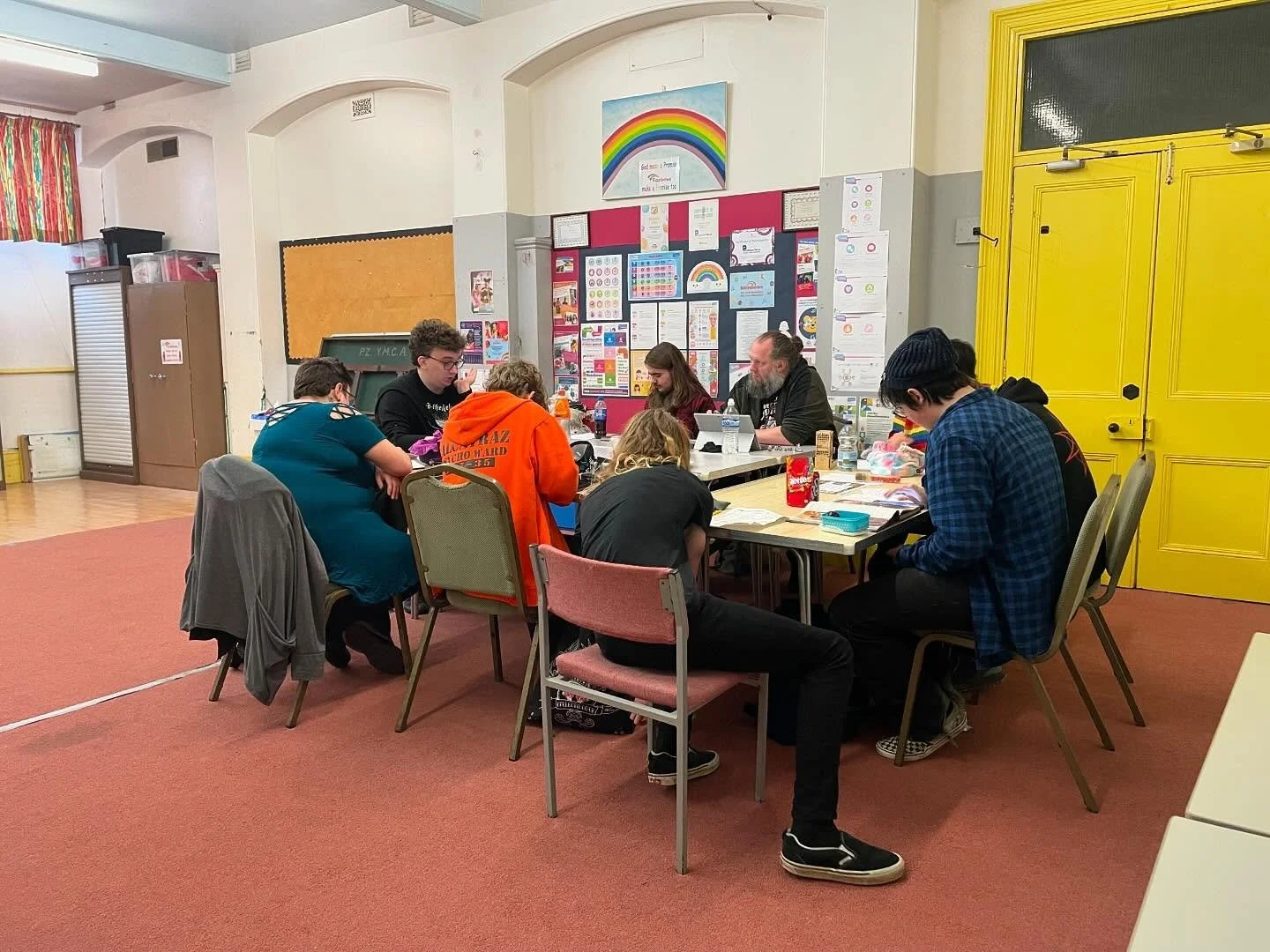 Seven players of all ages sit around a table playing D&D at truro methodist church in cornwall