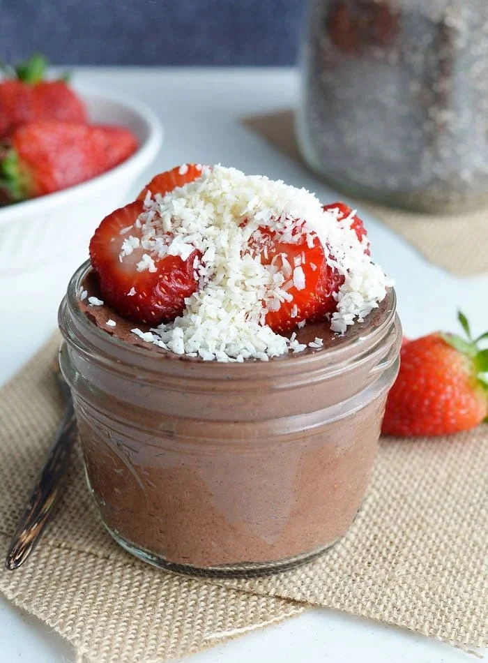 Chocolate mousse topped with sliced strawberries and grated white chocolate in a glass jar.