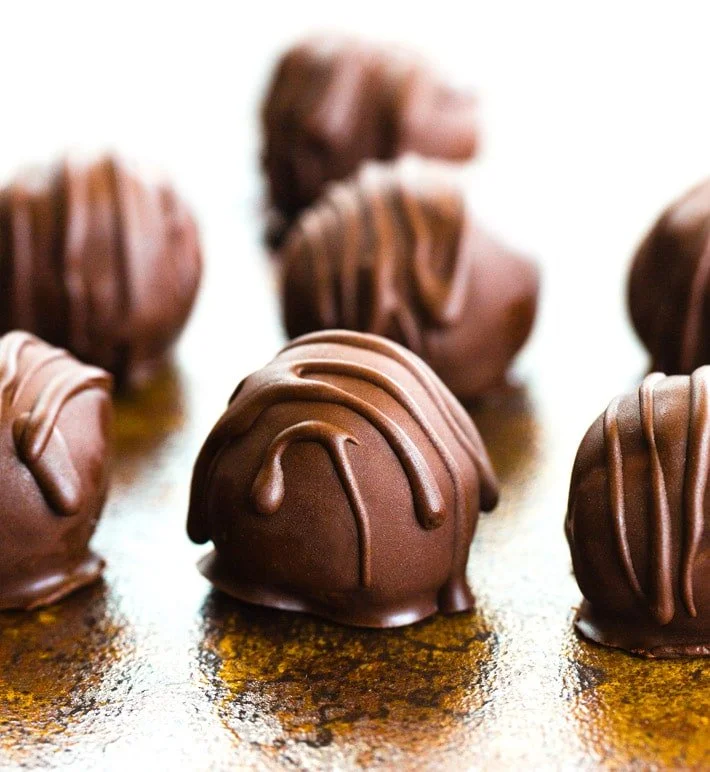 Close-up of chocolate truffles with drizzled chocolate on top, arranged on a surface.