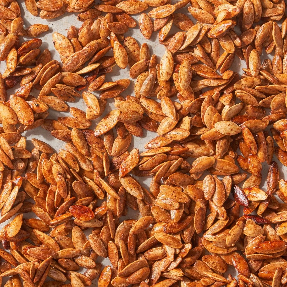 Close-up of roasted sunflower seeds on a white surface.