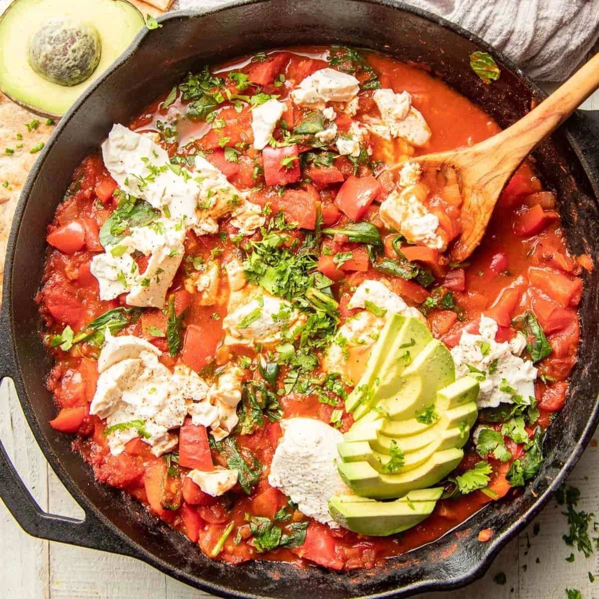 cast iron pan of vegan shakshuka topped with avocado