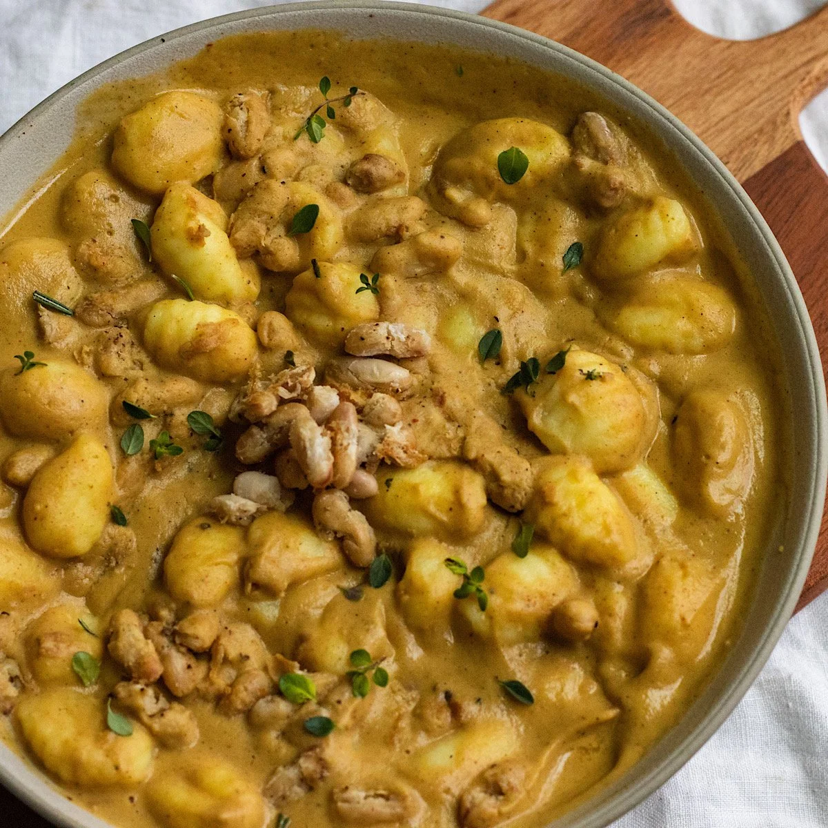 Potato stew garnished with fresh herbs in a ceramic bowl.